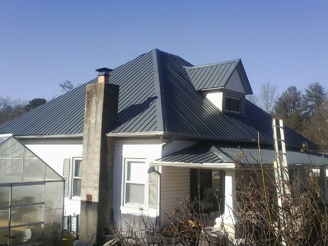 Dark blue standing seam metal roof on a white farmhouse with dormer — Slate & Tile Roof Repair by Roofing Brothers in Millmont