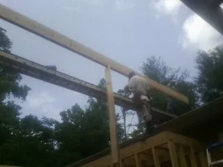Carpenter setting a ridge beam over a new addition frame — Ice Dam Removal by Roofing Brothers in Millmont