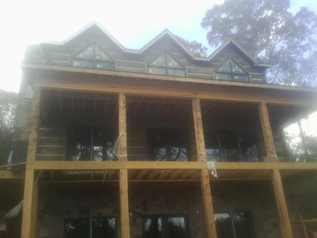 Dormers and porch framing on a large log home under construction — Roof Coating work by our crew in Millmont