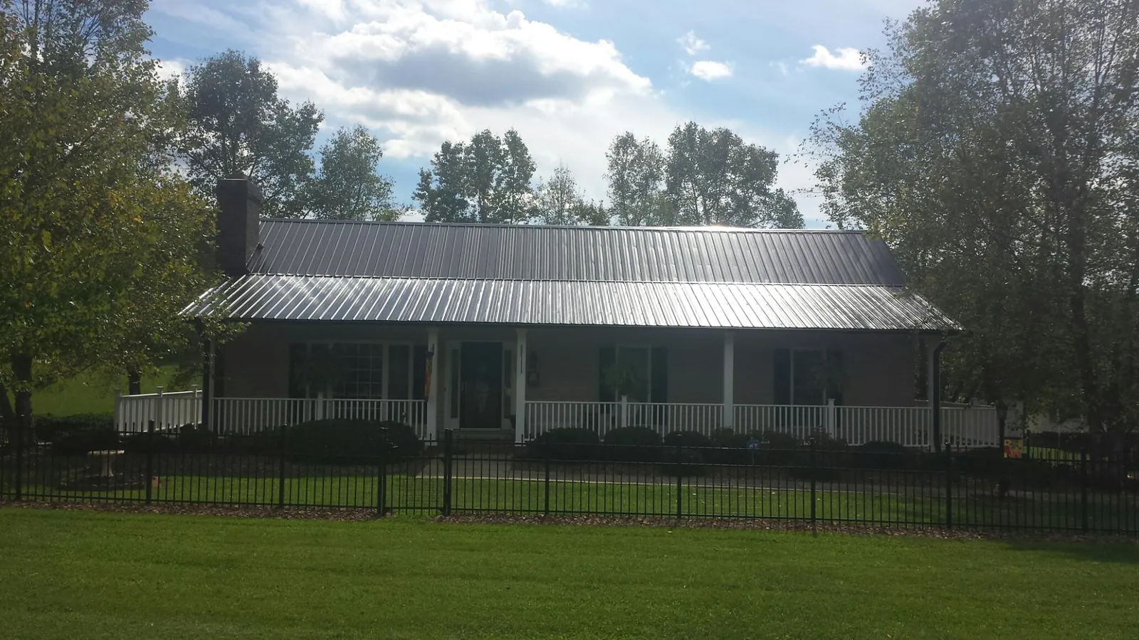 Gray metal roof on a brick ranch with a full width front porch — Gutter Guard Installation work by our crew in Millmont