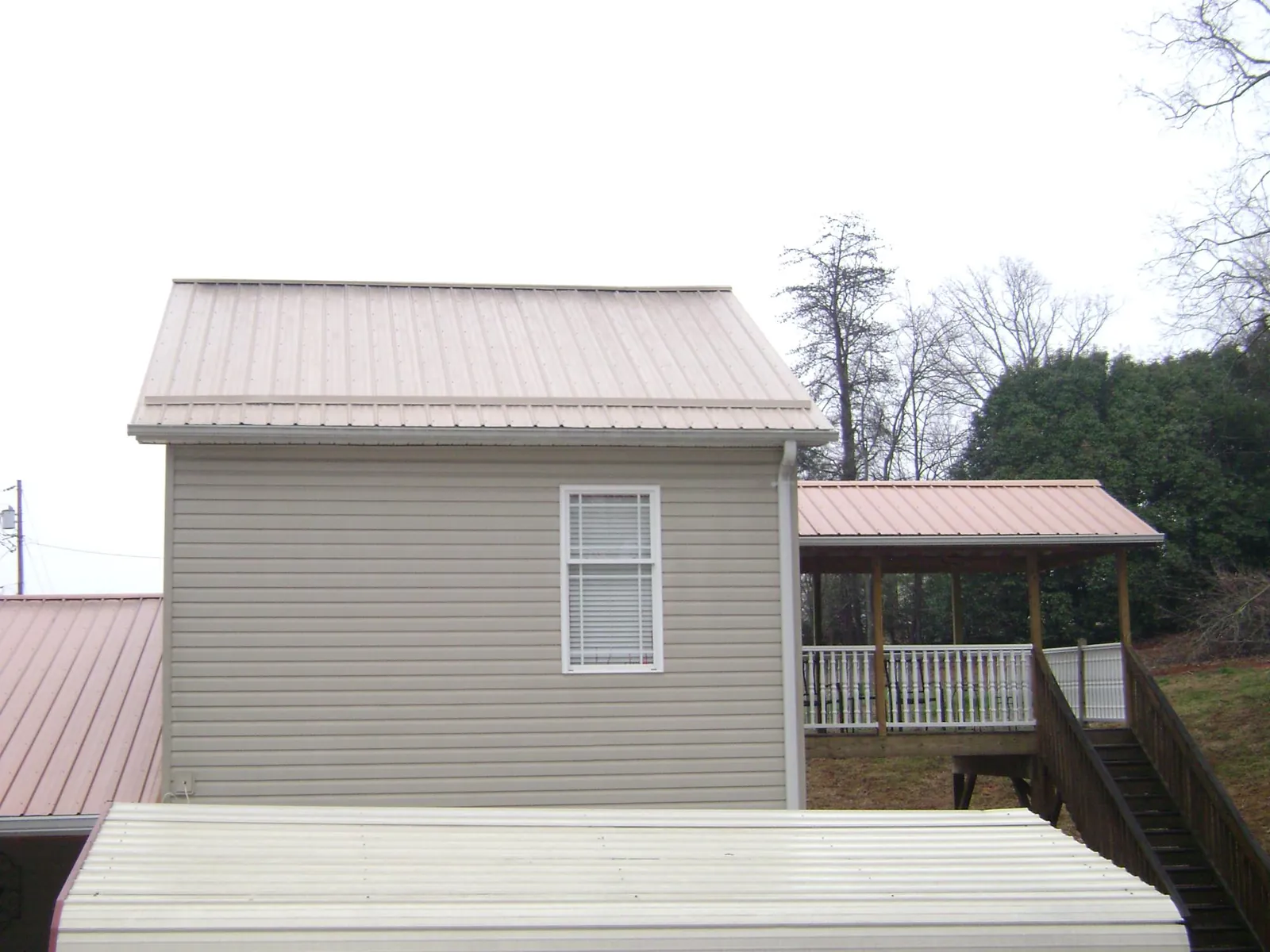 Tan metal roofs on a two story addition and attached porch, from a Roof Replacement job in Millmont